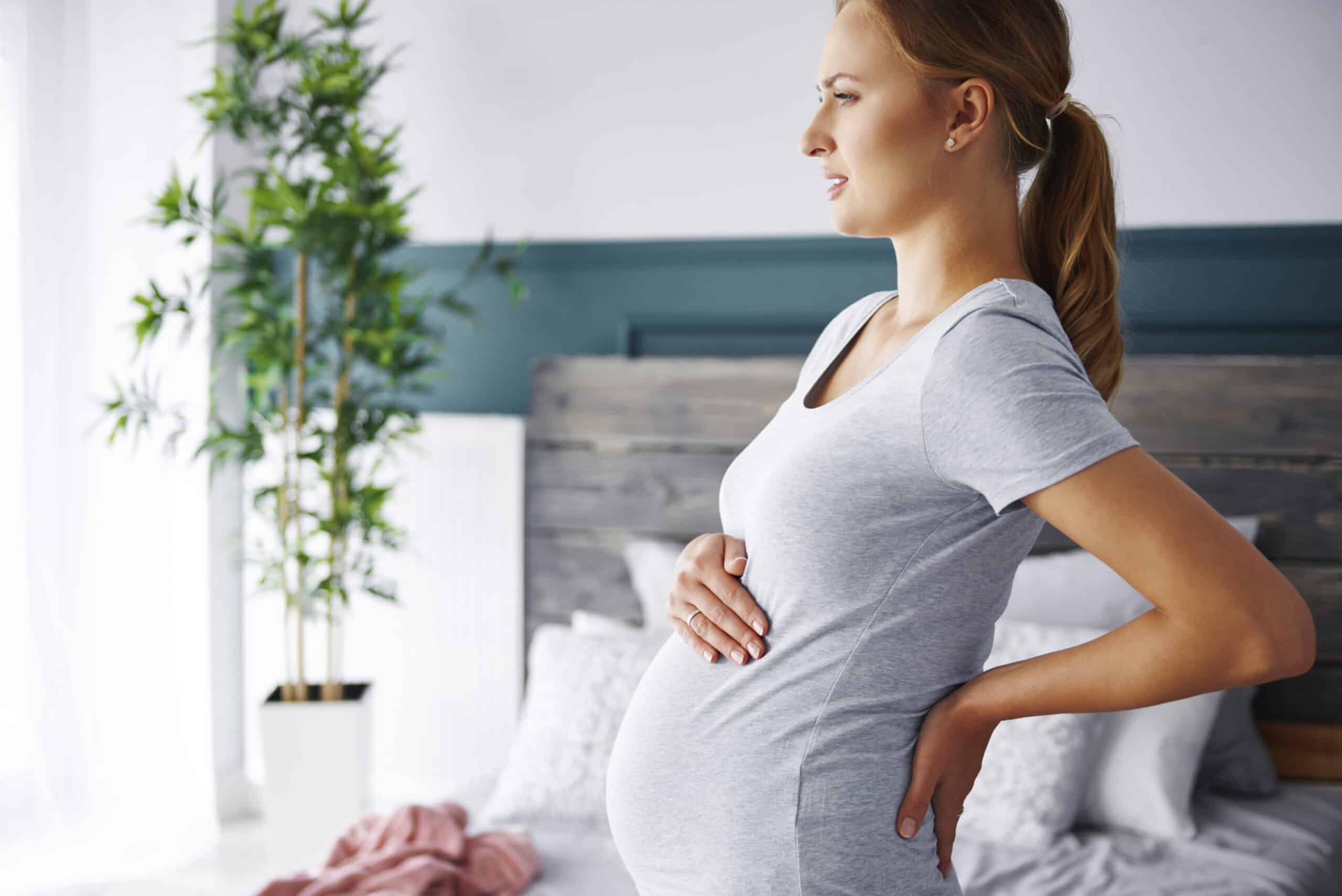 pregnant woman holding stomach and back