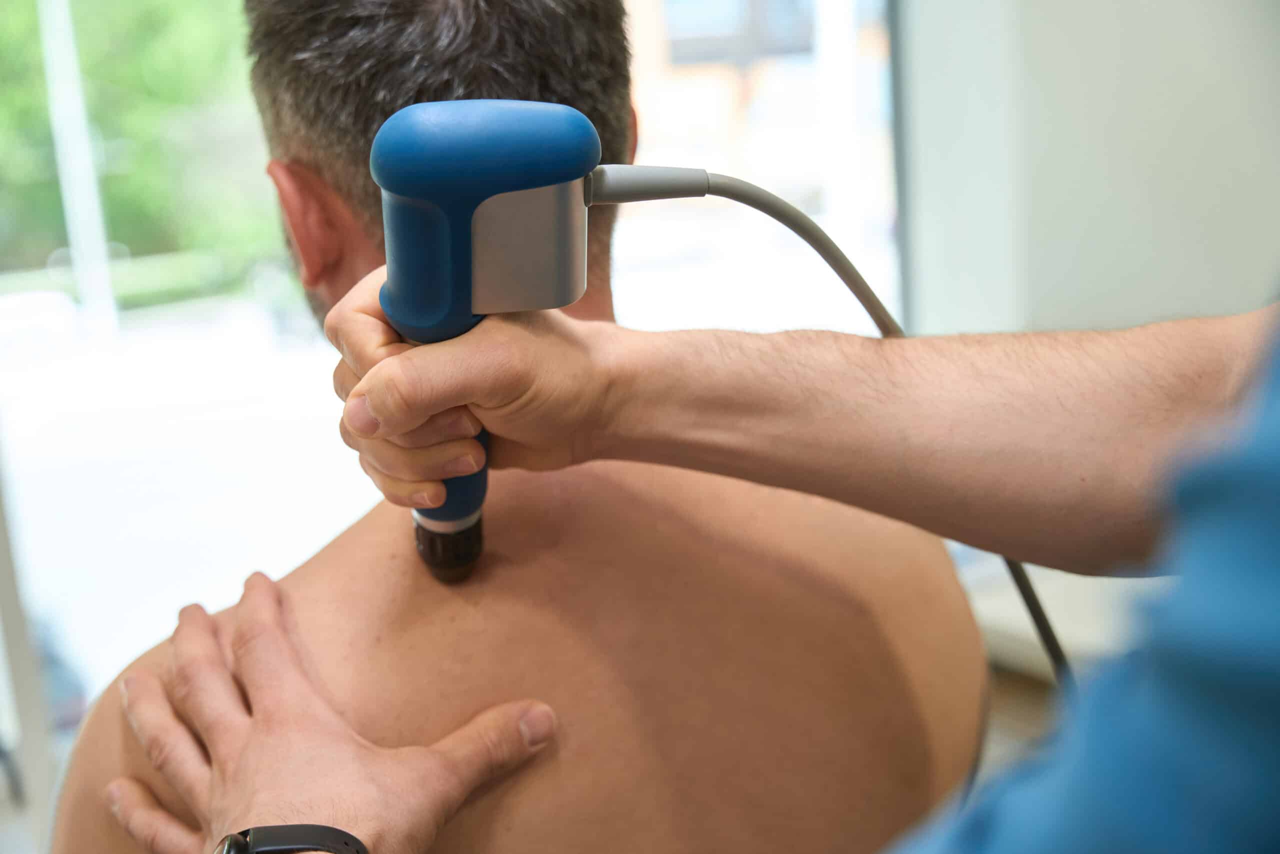 pressure wave device being used on a man's upper back